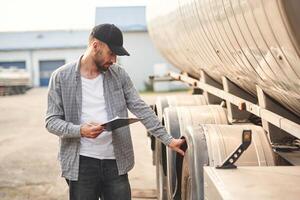 Black colored notepad, in hands. Young truck driver in casual clothes photo