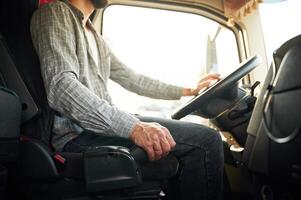 Side, view, sitting inside the vehicle. Young truck driver in casual clothes photo