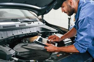 Using tablet. Auto ,mechanic,working in, garage. Repair service photo
