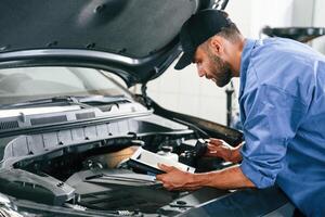 Using ,tablet. Auto mechanic working in ,garage. Repair service photo