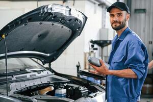Grey ,colored oil can in, hands. Auto mechanic working in garage. Repair service photo