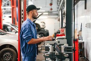 Standing ,by ,computer terminal. Auto mechanic working in garage. Repair service photo