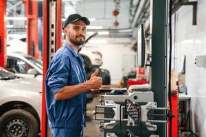 Standing by computer terminal,. Auto ,mechanic working in garage. Repair service photo
