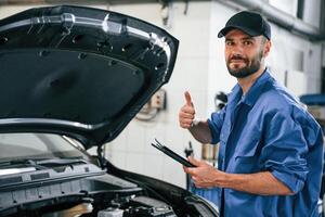 With ,tablet in hands.. Auto mechanic working in garage. Repair service photo