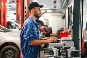 Standing ,by, computer terminal. Auto mechanic working in garage. Repair service photo