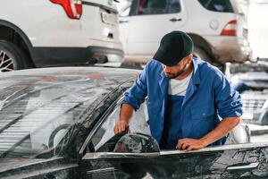 Dirty car is moved by auto mechanic that is in garage. Repair service photo