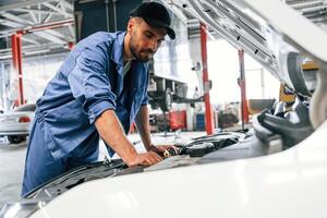 Troubleshooting process. Auto mechanic working in garage. Repair service photo