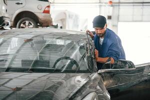 Moving the dirty car that, need washing. Auto mechanic working in garage. Repair service photo