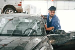 Moving the dirty ,car that need washing. Auto mechanic working in garage. Repair service photo