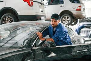 Dirty car is moved by, auto mechanic that is in garage. Repair service photo