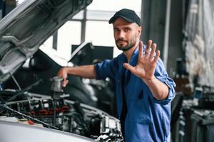No trespassing, don't disturb hand gesture. Auto mechanic working in garage. Repair service photo
