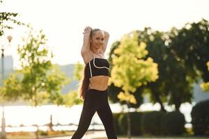 Preparing for the, fitness session.. Beautiful young woman in sportive clothes is in the park at sunny daytime photo