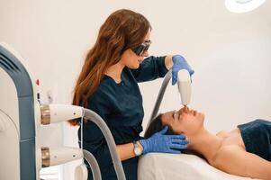 Lying down. Getting photo rejuvenation procedure at cosmetology clinic
