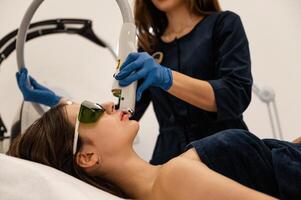 In, green, protective eyewear. Getting photo rejuvenation procedure at cosmetology clinic. Women in beauty salon