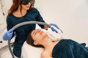 Woman is getting ,LPG hardware massage in beauty salon. Getting photo rejuvenation procedure at cosmetology clinic
