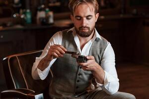 Cleaning hair clipper. Handsome barber, is ,in the salon photo
