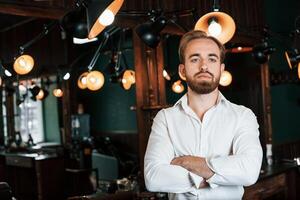Standing with ,arms crossed. Handsome, barber is in the salon photo