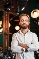 Standing with arms ,crossed. Handsome barber is in the salon photo