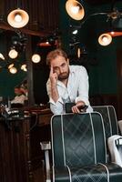 Leaning on th,,e chair. Handsome barber is in the salon photo