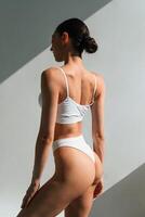In the, sunlight. Young woman with slim body type is in fitness clothes in the studio photo