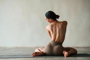 Back view,, showing the spine, without bra. Young woman with slim body type is in fitness clothes in the studio photo