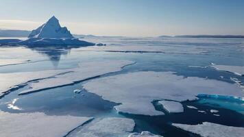 A serene icy landscape featuring a large iceberg and floating ice in a tranquil sea. photo