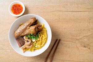 Egg noodles served dry with braised duck on wooden background photo