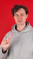 man shakes index finger hand in front showing sign ban, rejected gesture. Isolated red background studio shot. Concept - avoid, danger, disapproval, negative emotions, must not, impossible video