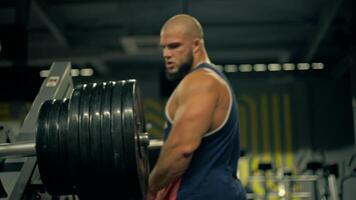 bald athletic man is focused on executing leg exercises gym. He is removes weights from leg press machine during midday training session video