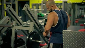 Focused on his routine bald athletic man removes weights on leg press machine while adjusting equipment for challenging set video
