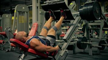 bald athletic man beard engages in leg exercises gym utilizing leg press machine build strength and endurance during his workout session focused on fitness and health video