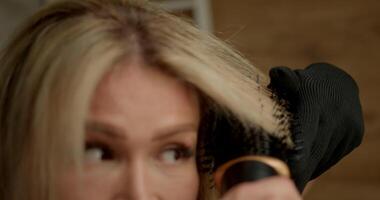 In warm indoor environment woman uses hairdryer equipped unique curling attachment create bouncy curls. Her attention focuses on styling process video