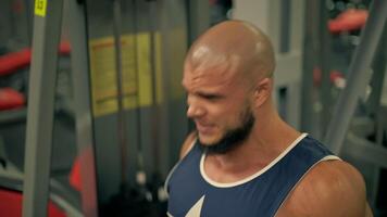 Bald athletic man beard focuses on does leg extensions. Muscles tense as he pushes through his routine showcasing dedication fitness and strength training video