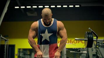 Bald athletic man beard focuses on his leg workouts in gym setting. He is engaged in lifting weights intensity and determination. atmosphere is energetic and motivating. posing for the camera video