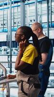 Vertical Engineer in photovoltaics smart factory talking with coworker, diagnosing malfunctioning IoT sensors. Industry 4.0 solar panels plant colleagues doing brainstorming to reduce downtime, camera A video