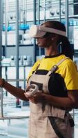 Vertical Smart factory engineer implements automated workflows and control systems using virtual reality, computerizing operations. Technician integrates sensors into production using VR headset, camera A video
