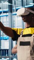 Vertical Smart photovoltaics factory expert wearing VR headset looks at system performance metrics. Solar panels plant worker uses virtual reality tech to track energy production through IoT sensors, camera A video