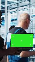 Vertical Engineer using green screen laptop in industry 4.0 industrial plant to install machinery. Robotics technician using mockup notebook in smart factory calibrating IoT sensors, panning shot video