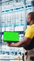 Vertical Smart factory specialist using mockup laptop to test automated systems and ensure reliability. Woman uses isolated screen notebook to identify bottlenecks and optimize equipment, camera A video