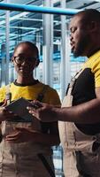 Vertical Smart factory engineering team brainstorming, testing automated systems to ensure reliability. Industry 4.0 industrial plant workers identify bottlenecks and optimize gear based on data, camera A video