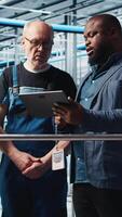 Vertical Engineers talking with manager overseeing smart factory, showing collected metrics. Technicians receiving feedback from supervisor in industry 4.0 industrial plant equipped with sensors, camera A video