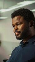 Vertical Employee looking over revenue figures on documents in office. Accountant in office focused on comparing company statistical numbers, working hard to finish job before deadline, camera B video