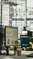 Vertical Financial charts and KPI metrics on displays in office, panning shot. Vibrant and collaborative modern workspace with computer screens displaying data analytics, panning shot video