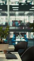 Vertical Business graphs and performance metrics on monitors in workplace, handheld camera shot. Office desk setup in bright corporate environment with monitors displaying data analytics, panning shot video