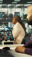 Vertical Worker in office talking with colleagues during internet videocall. Employee at work discussing with business partners during remote teleconference meeting, analyzing metrics, camera B video