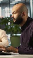 Vertical Arab man in office reviewing financial graphs, analyzing key performance indicators. Middle Eastern employee in workspace looking over data trends and strategic insights, camera A video