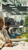 Vertical Joyous coworkers having fun in vibrant office while reviewing financial graphs. Cheerful colleagues sharing jokes while working, looking over data trends and strategic insights, camera B video