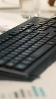 Vertical Modern workspace with analytical data paperwork documents in bright office environment with potted plants. Tablet on desk with digital statistics charts displayed on screen, close up shot video