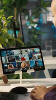 Vertical Worker in office talking with colleagues during internet videocall. Employee at work discussing with business partners during remote teleconference meeting, analyzing metrics, camera A video
