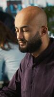 Vertical Happy man in office reviewing financial graphs, pleased after seeing good key performance indicators. Cheerful employee celebrating positive KPIs and data trends, camera A video